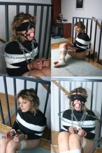 Steel Restrained - Anita is handcuffed and thumbcuffed, attached with much chain to the railing and finally ballgagged and blindfolded.